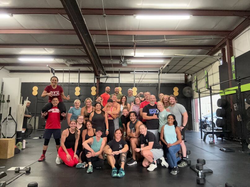 A smiling group of participants gathered together after a group training session in a gym